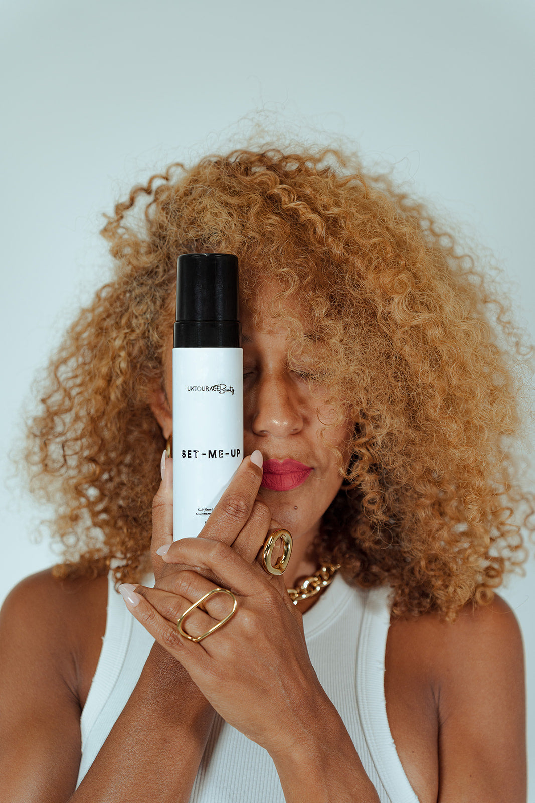 Woman holding a hair product with a neutral background